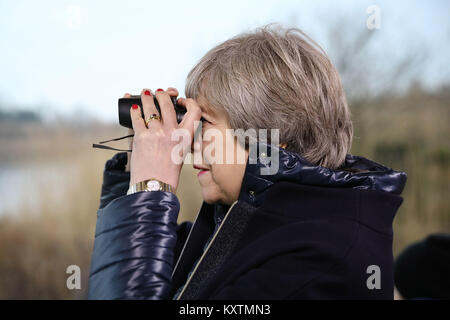 Il primo ministro Theresa Maggio guarda attraverso un binocolo durante una visita al London Wetland Centre nel sud ovest di Londra, dove ha impostato la sua visione per la protezione dell'ambiente. Foto Stock