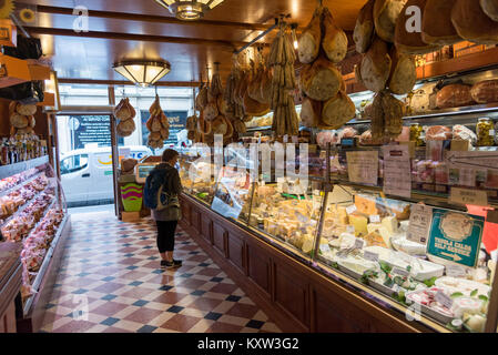 Una donna in cerca di cibo sul display insode un tradizionale della salumeria italiana la vendita di formaggio, prosciutto e charcutterie in Bologna Otaly Foto Stock