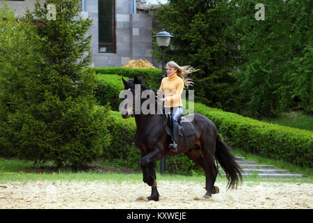 Ritratto di giovane donna bionda di equitazione in campagna Foto Stock