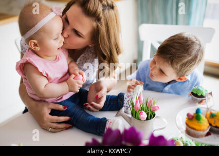 Dei bambini felici con la madre di mangiare i tortini Foto Stock