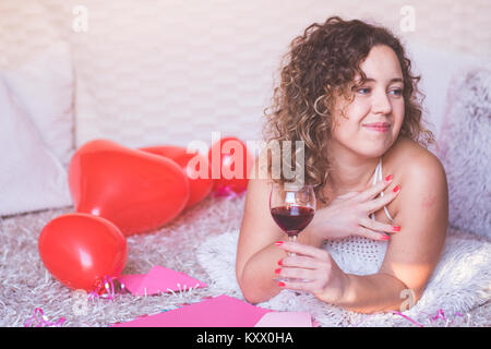 Giovane bella donna con in mano un bicchiere di vino e sognare il giorno di San Valentino. Foto Stock