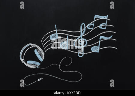 Cuffie con filo e note musicali disegnato sulla lavagna Foto Stock