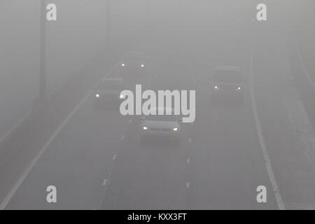 Cars driving senza fari antinebbia in autostrada su un nebbioso giorno nel Regno Unito Foto Stock