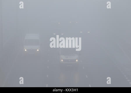 Auto e furgoni guida su autostrada senza fari antinebbia su un nebbioso giorno nel Regno Unito Foto Stock