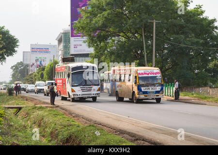 Autobus e altri veicoli auto giù Waiyaki via verso la città di Nairobi come pedoni attendere alla croce, Nairobi, Kenia Foto Stock