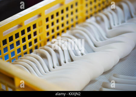 Close up di porcellana bianca cucchiai in un giallo vassoio di plastica in una porcellana giapponese workshop. Foto Stock