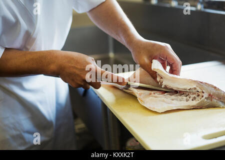 Close up di chef lavorano a un contatore a un I sushi giapponesi La cucina del ristorante, affettare il filetto di pesce. Foto Stock