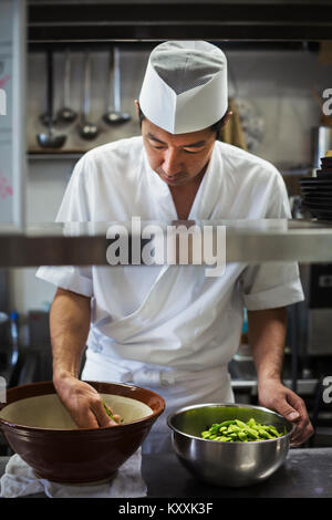 Lo Chef lavora nella cucina di un I sushi giapponesi La cucina del ristorante, preparare una ciotola di edamame fagioli. Foto Stock