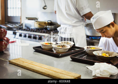 Due chef lavorano a un contatore a un I sushi giapponesi La cucina del ristorante. Foto Stock