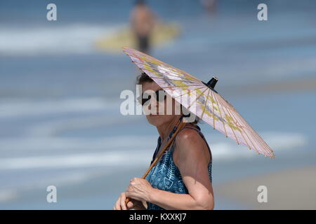 Donna con parasole sfumature dal sole sulla spiaggia Foto Stock