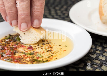 Persona pane immersione in un esperto di olio di oliva su una piastra bianca Foto Stock