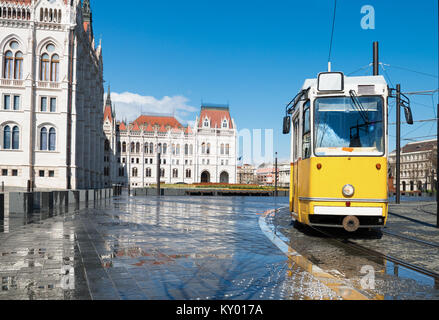 Tram storico passando dal palazzo del parlamento a Budapest, Ungheria. La messa a fuoco in primo piano compresi tram. Foto Stock