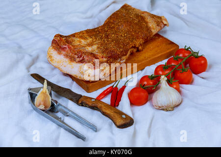 Materie fette di pancetta con giallo a secco con spezie sulla lavagna bianca Carne di maiale cruda per decapaggio. Foto Stock