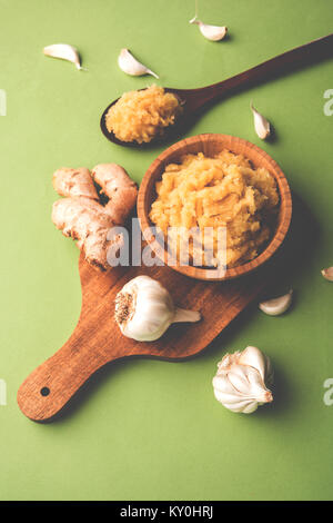 Purea di zenzero fresca / pasta di Adrak in ciotola bianca con tutto crudo su sfondo bianco. Messa a fuoco selettiva Foto Stock