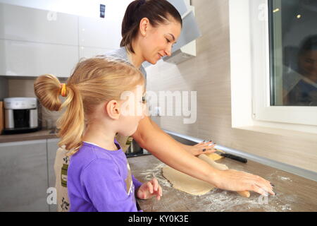 Mom figlia insegna a cucinare. Madre con bambina fare torta. Foto Stock