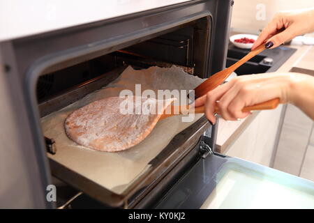 La donna prende la torta dal forno. La cottura a casa. Foto Stock