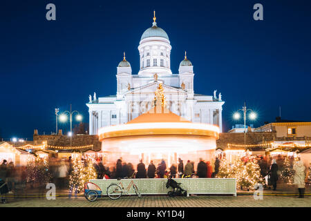 Helsinki, Finlandia. Xmas Mercatino di Natale in Piazza del Senato con la giostra di vacanza e il famoso punto di riferimento è la Cattedrale luterana nella notte d'inverno. Foto Stock