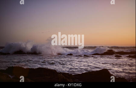 Panorama di seascape in tempo al tramonto. Onde infrangersi sulle rocce al tramonto sull'oceano Foto Stock