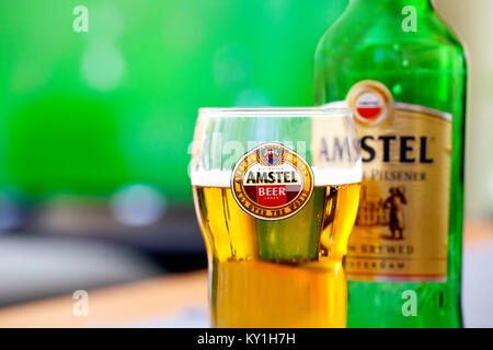 SOFIA, BULGARIA - 08 maggio, 2017: vetro di Amstel e bottiglia - sfondo del televisore la riproduzione del gioco del calcio.Amstel Pilsener Premium è un noto internazionalmente br Foto Stock