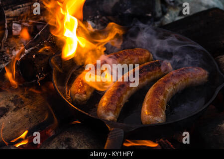 Live cottura a fuoco succosa salsicce oltre il fuoco. Foto Stock