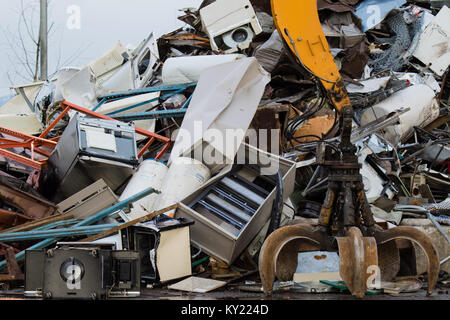 Potente meccanico afferra il braccio è la forza che muove il vecchio rottame metallico e utilizzati apparecchi elettrodomestici in un cantiere di scarto. Foto Stock