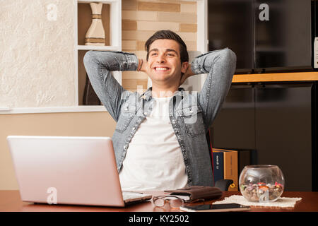 Giovane uomo lavora con soddisfazione in casa. Concetto di lavoro online, shopping on line. Foto Stock