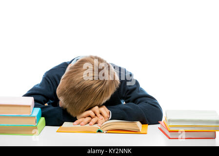 Una stanca scolaro si è addormentato mentre la lettura di un libro a tavola Foto Stock