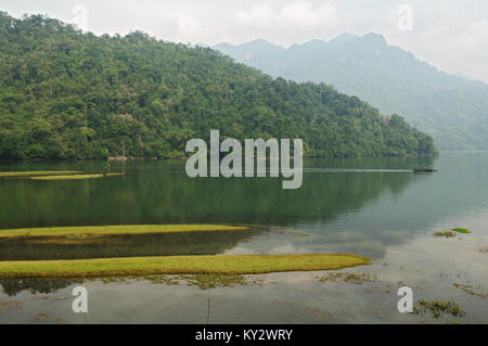Piccola barca su Ba essere Lago di prima mattina, Ba essere National Park, Nord Vietnam Foto Stock