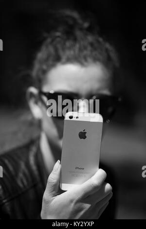 DORKOVO, BULGARIA - NOVEMBE:R 13, 2017: bianco e nero illustrativi immagine editoriale della giovane donna tenendo iPhone in mani con Apple logo Inc Foto Stock