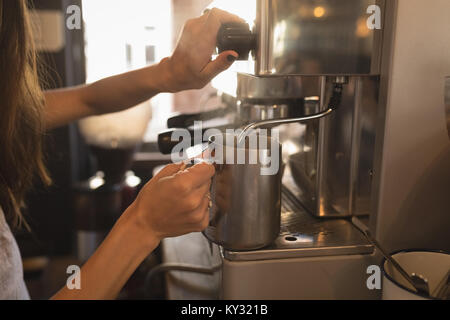 Barista latte di cottura a vapore in corrispondenza della macchina da caffè Foto Stock