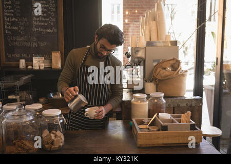 Barista versando il latte in una tazza al bancone Foto Stock