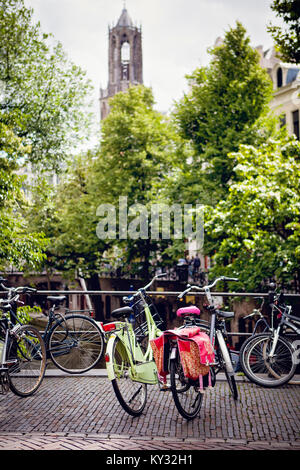 Centro di Utrecht. Biciclette su un ponte sul canale con la Torre del Duomo in background. Biciclette colorate con paniers. Foto Stock