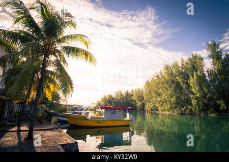 Piccola barca da pesca nel porto di tropicale con Palm tree in primo piano, Seicelle Foto Stock