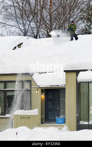 Un uomo la rimozione di neve dal tetto di una casa, Quebec City in inverno Foto Stock