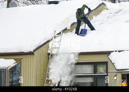 Un uomo la rimozione di neve dal tetto di una casa, Quebec City in inverno Foto Stock
