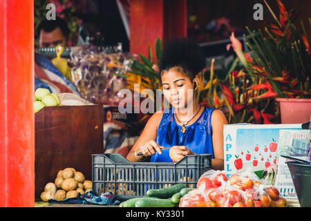 Giovane donna africana la pelatura di patate sul mercato Foto Stock