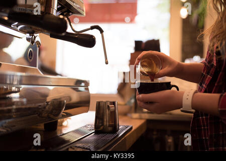 La sezione centrale del barista versando il caffè in tazza Foto Stock