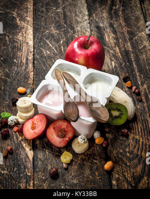 Yogurt fresco con frutta e noci. Su uno sfondo di legno. Foto Stock