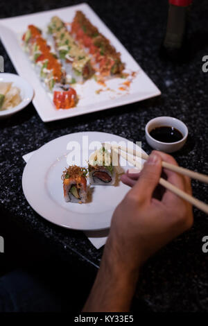 Man picking up sushi con bacchette Foto Stock