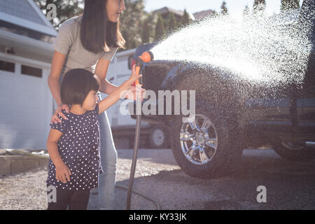 Madre e figlia di lavaggio di un automobile con un getto di acqua ad alta pressione Foto Stock