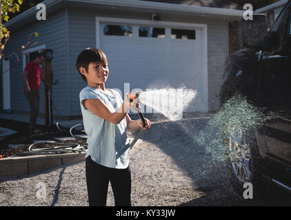Ragazzo il lavaggio auto con un getto di acqua ad alta pressione Foto Stock
