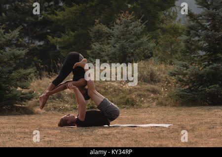 Sportivo da donna pratica di acro yoga su un terreno aperto Foto Stock