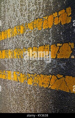 Le linee gialle su asfalto screpolato. Foto Stock