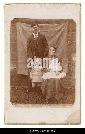 Ritratto originale da cartolina di famiglia con bambini piccoli, all'esterno di fronte alla tela, circa 1912, Regno Unito Foto Stock