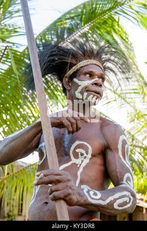 Headhunter di Asmat tribù con una pittura tradizionale su una faccia, copricapo da casuario piume. Giugno 28, 2012. Jow Village, Asmat Foto Stock