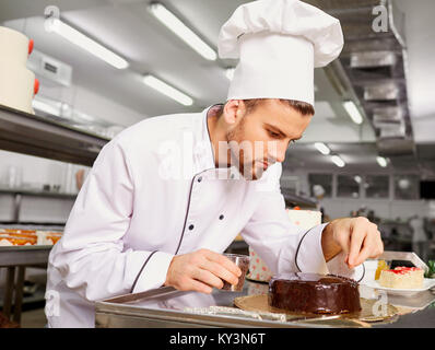 Uomo di una pasticceria con una torta nelle sue mani in pasta. Foto Stock