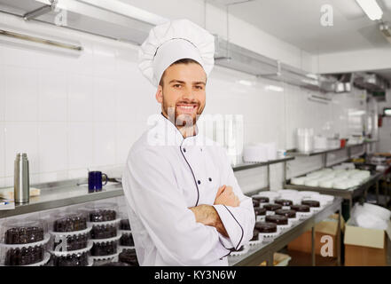 Uomo di una pasticceria con una torta nelle sue mani in pasta. Foto Stock