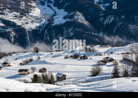 In legno capanne alpine in località sciistica Serfaus Fiss, in posizione Ladis in Austria con montagne innevate con la nebbia Foto Stock