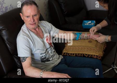Ex calciatore internazionale Paolo "gazza" Gascoigne, in fase di preparazione da parte di un infermiere prima di subire una infusione di nutriente alla Corte Cassiobury, una droga e alcool clinica di riabilitazione a Watford, Inghilterra. Il protocollo pionieristico, coinvolgendo un prodotto noto come NAD+, aiuta a riparare il cervello e il corpo è stato introdotto per il Regno Unito da John Gillen, managing director di Londra-base ferma Bionad Ltd. I pazienti vengono sottoposti a vari infusi, che può richiedere fino a diverse ore per il completamento, sotto la supervisione di un medico della clinica. Foto Stock