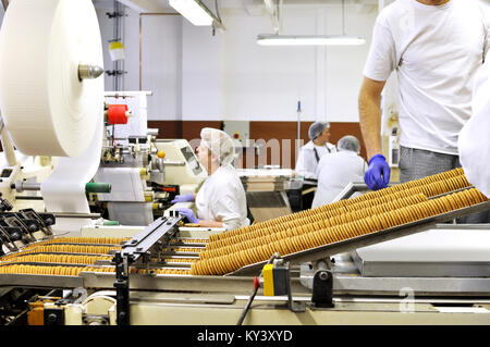 Lavoratori ordina i biscotti su un nastro trasportatore in una fabbrica - produzione nell'industria alimentare Foto Stock